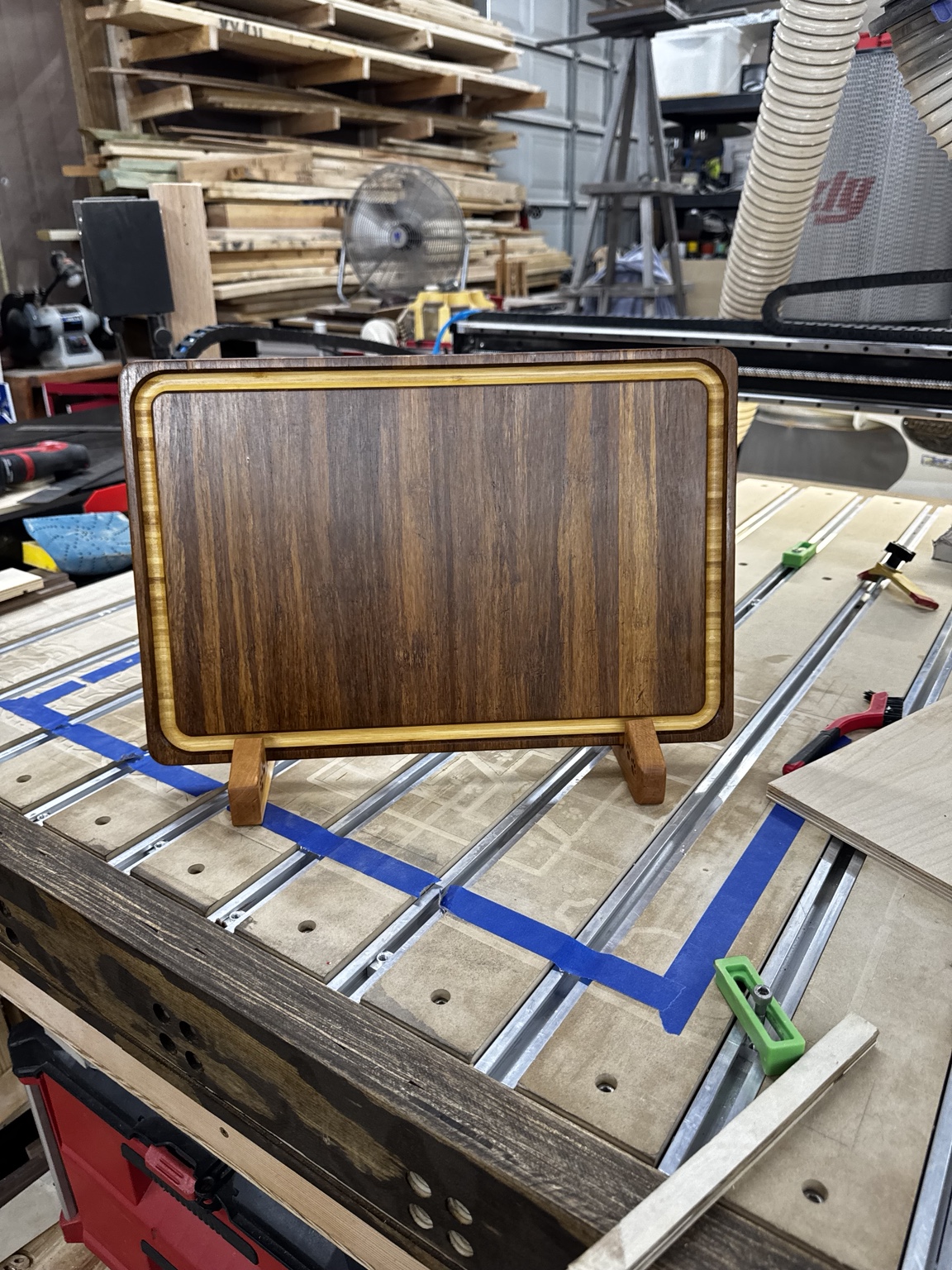 Actual WoodenYou BamX Bourbon cutting board front with routed juice groove, shown on the cherry display supports in the shop